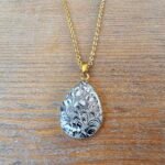 Collier goutte doré à motifs noirs en assiette ancienne – Dentelle d’Encre